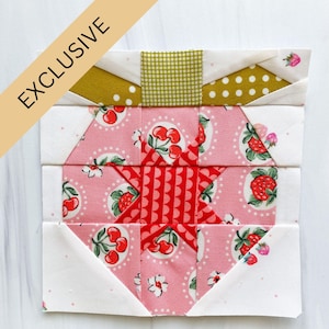 Peut inclure: Un bloc de courtepointe patchwork avec une étoile rouge et blanche au centre, entourée d'un tissu rose à imprimé cerises. Le bloc est bordé d'un tissu blanc à petits pois et d'un tissu doré à pois blancs.