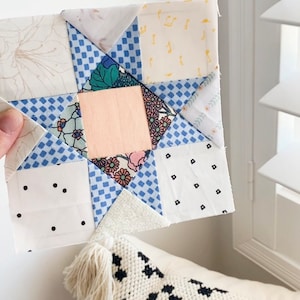May include: A patchwork quilt block featuring a star design with various blue, white, and pink fabrics. The block is made up of squares and triangles, and the star is surrounded by a border of smaller squares.