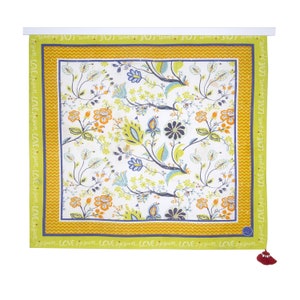 May include: A square tapestry with a floral pattern in shades of blue, green, orange, and yellow. The tapestry has a yellow and orange border with the words "LOVE" repeated around the edge.