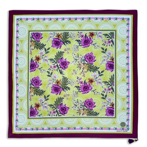 May include: Square scarf with a floral pattern. The scarf features a light green background with purple flowers and green leaves. The border is a deep burgundy with a decorative pattern in white and light green. The scarf has a tag with the initials "SL" and the word "LOVE".