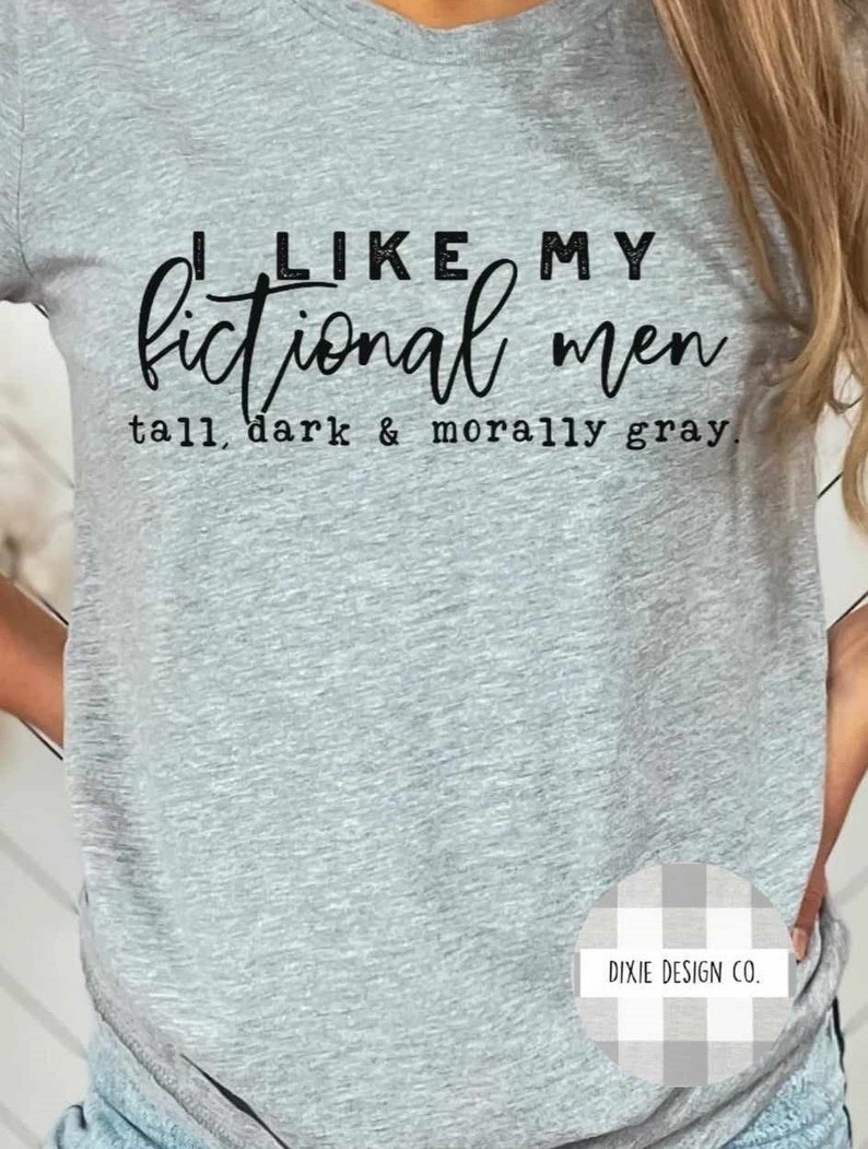 May include: Gray t-shirt with black text that reads "I like my fictional men tall, dark & morally gray."  The bottom right corner of the shirt has a white and gray gingham pattern with the text "DIXIE DESIGN CO."