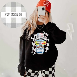 May include: Black sweatshirt with a checkered pattern and a graphic of a beer can with a mustache and sunglasses. The text on the can reads "Busch Light" and "Raise Hell Praise Beer".