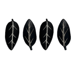 May include: Four black leaf-shaped ceramic dishes with white lines.