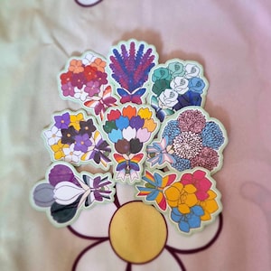 Op de afbeelding: Een set van acht kleurrijke bloemboeket stickers. Elke sticker heeft een andere bloemschikking met verschillende kleuren en patronen. De stickers zijn perfect om een vleugje whimsy toe te voegen aan dagboeken, laptops of waterflessen.