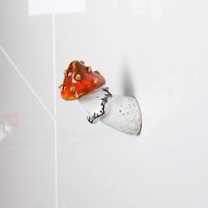 Puede incluir: Armarios de cocina blancos con tiradores de cajones en forma de hongo. Los tiradores en forma de hongo son rojos y blancos con manchas marrones.