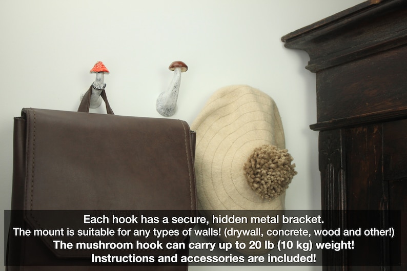 May include: Two white ceramic mushroom hooks with red and brown tops mounted on a white wall. A brown leather bag hangs from one hook and a beige hat hangs from the other. The text below reads: "Each hook has a secure, hidden metal bracket. The mount is suitable for any types of walls! (drywall, concrete, wood and other!) The mushroom hook can carry up to 20 lb (10 kg) weight! Instructions and accessories are included!"