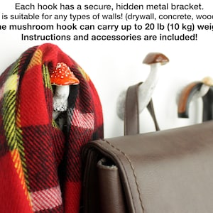 May include: Three mushroom-shaped hooks with a white finish and red and white mushroom caps. The hooks are mounted on a white wall and a brown leather bag is hanging from one of the hooks. The text "Each hook has a secure, hidden metal bracket. The mount is suitable for any types of walls! (drywall, concrete, wood and other!) The mushroom hook can carry up to 20 lb (10 kg) weight! Instructions and accessories are included!" is visible at the top of the image.
