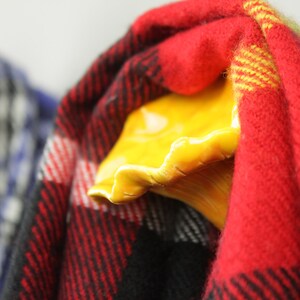 May include: Two ceramic hooks in the shape of a hand, painted yellow, with a red and black plaid scarf hanging on one hook and a blue and white plaid scarf hanging on the other hook.