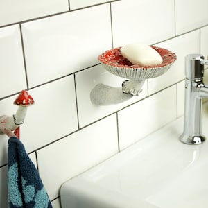 Amanita shelf and hook on the background of white tiles in the bathroom. This couple looks great together! White shell, white tiles, red hats and black edges of skirts.