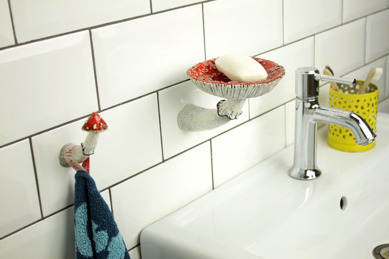 Amanita shelf and hook on the background of white tiles in the bathroom. This couple looks great together! White shell, white tiles, red hats and black edges of skirts.