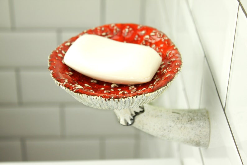 The soap is in a fly agaric hat. The hat has a small indentation in the center for convenience. The leg of the mushroom shelf is attached to the wall, as if a fly agaric grows out of it.