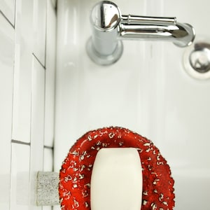 Top view: a shelf with soap, which only holds on a leg and therefore looks like a real mushroom has come out of your wall. His hat does not touch the wall and soap is free in it.