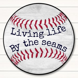 May include: White and red baseball-themed round sign with the text "Living life by the seams".