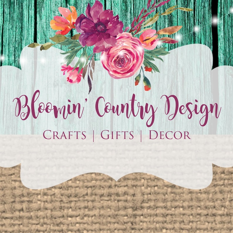 Op de afbeelding: Een wit bord met een bloemenontwerp en de tekst "Bloom'n Country Design" met de woorden "CRAFTS | GIFTS | DECOR" eronder. Het bord is op een rustieke houten achtergrond.