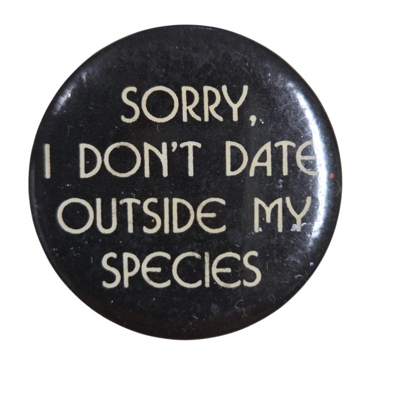 Peut inclure: Un bouton rond noir avec du texte blanc qui dit "SORRY, I DON'T DATE OUTSIDE MY SPECIES." Le bouton a une apparence l&eacute;g&egrave;rement us&eacute;e.