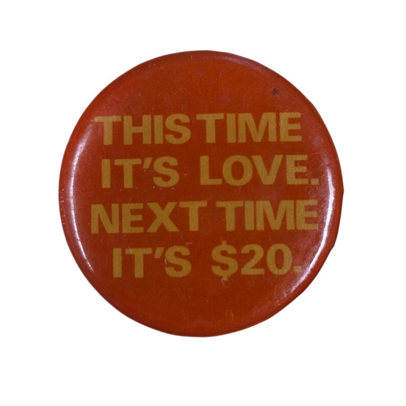 Peut inclure: Un bouton rond orange avec du texte dor&eacute;. Le texte dit : "THIS TIME IT'S LOVE. NEXT TIME IT'S $20."