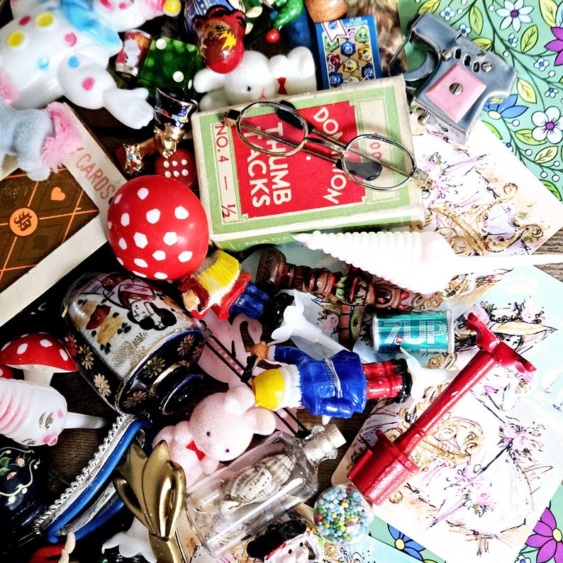 May include: A collection of vintage toys and trinkets, including a red and white polka dot ball, a red and blue toy soldier, a white seashell, a small red and white toy gun, a pair of glasses, a game of thumb jacks, a game of dominoes, and a small bottle with a seashell inside.