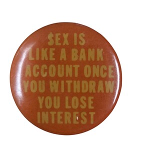 Peut inclure: Un bouton rond orange avec du texte dor&eacute;. Le texte dit : &laquo; SEX IS LIKE A BANK ACCOUNT ONCE YOU WITHDRAW YOU LOSE INTEREST. &raquo;