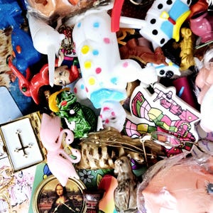 May include: A collection of colorful toys and trinkets, including a white and pink toy with polka dots, a green turtle, a pink flamingo, a blue and white toy with a red and white stripe, and a red and white toy with a blue and white stripe.