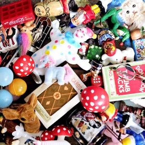 May include: A collection of vintage toys and trinkets, including a red and white polka dot mushroom, a white clown doll, a blue and white unicorn, a red and white Coca-Cola box, a deck of cards, and a pair of glasses.