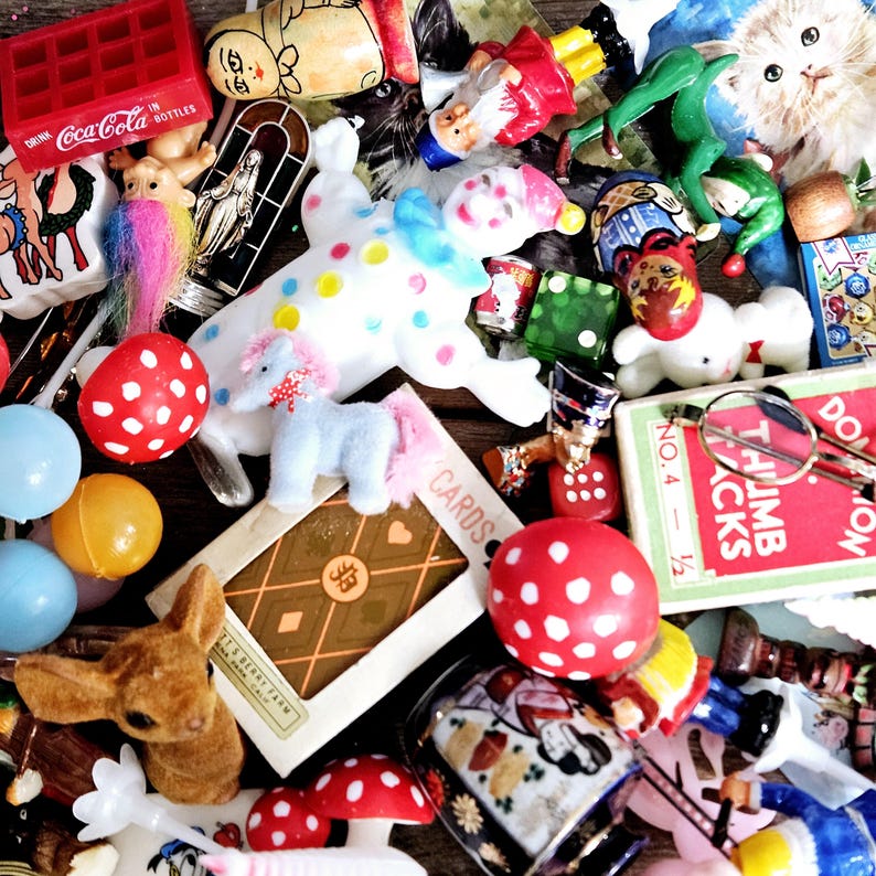 May include: A collection of vintage toys and trinkets, including a red and white polka dot mushroom, a white clown doll, a blue and white unicorn, a red and white Coca-Cola box, a deck of cards, and a pair of glasses.