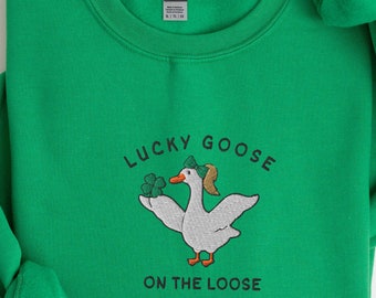 Puede incluir: Una sudadera de color verde kelly con el texto "Lucky Goose on the Loose" y una imagen bordada de un ganso con un sombrero verde y sosteniendo un trébol.