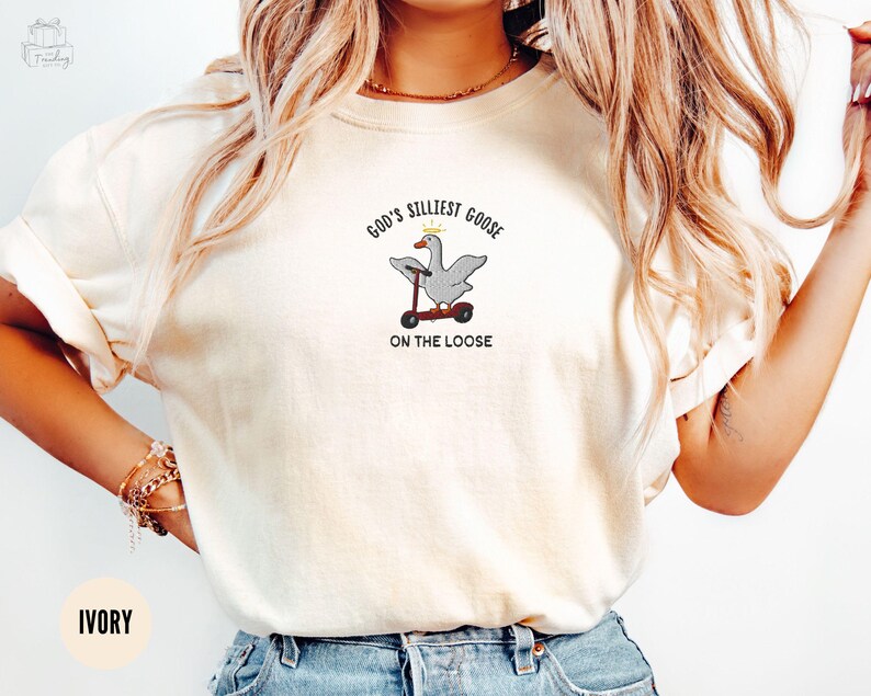 May include: A white t-shirt with the text "God's Silliest Goose On The Loose" and an embroidered image of a goose riding a scooter.