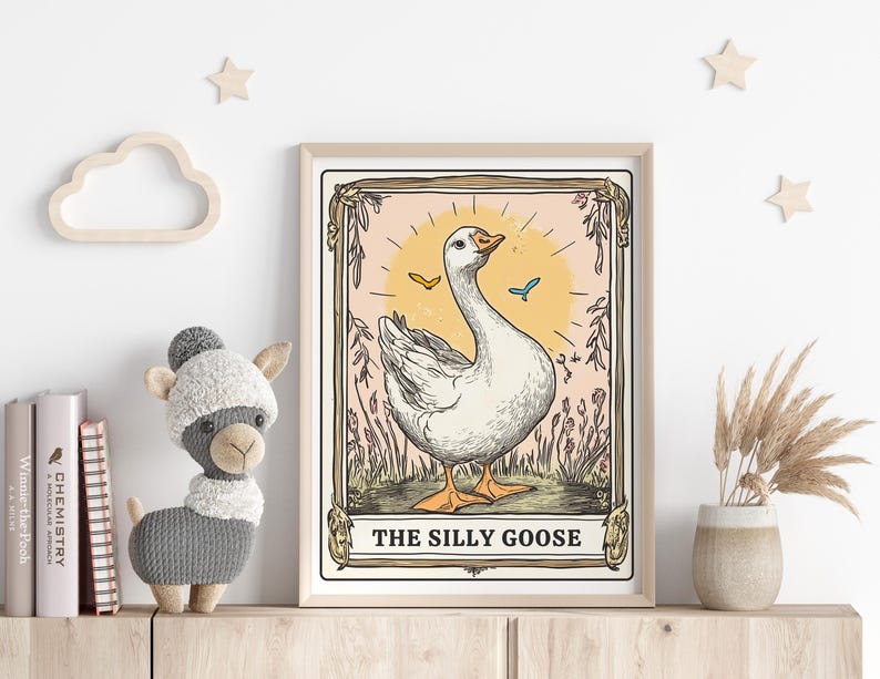 May include: A vintage-style illustration of a white goose with a yellow beak and blue eyes. The goose is standing on a green field with pink flowers and butterflies. The illustration is framed in a light brown frame with the text "The Silly Goose" at the bottom.