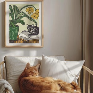 May include: A framed illustration of a black cat reading a book with yellow flowers in the background. A ginger cat is sleeping on a couch.