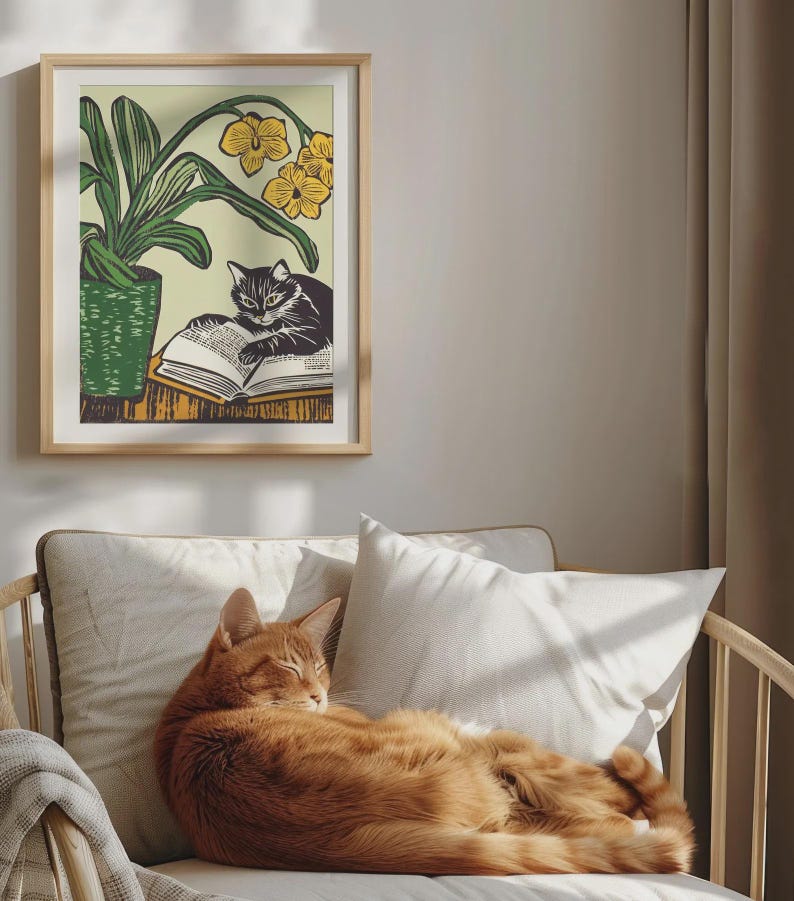 May include: A framed illustration of a black cat reading a book with yellow flowers in the background. A ginger cat is sleeping on a couch.