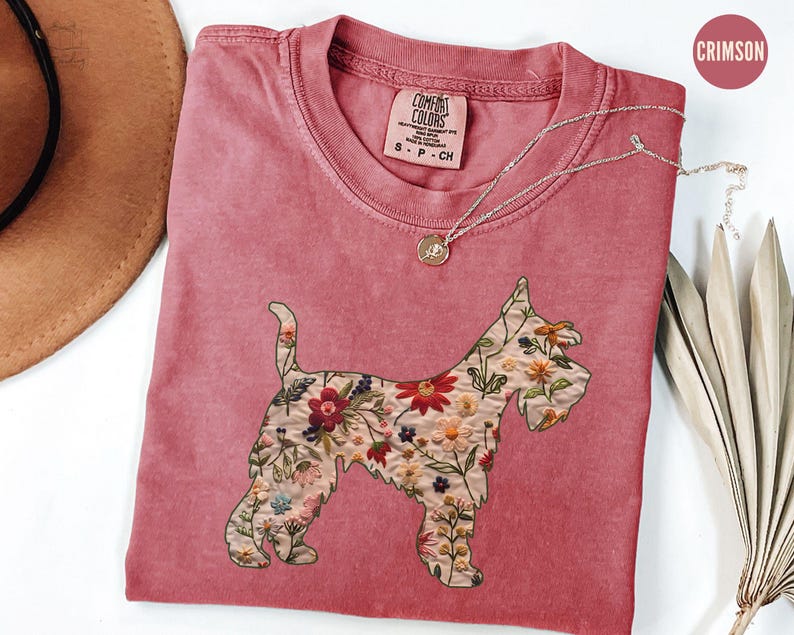 Puede incluir: Una camiseta roja carmes&iacute; con un dise&ntilde;o floral de un perro Schnauzer. La camiseta tiene el texto "COMFORT COLORS" en una etiqueta blanca.