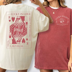 Può includere: T-shirt avorio e cremisi con la scritta "Lucky in Love" e "Emily's Bachelorette". La maglietta avorio presenta un disegno della regina di cuori, mentre la maglietta cremisi ha delle carte da gioco. Le magliette sono oversize.