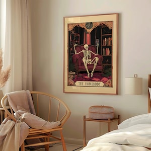 May include: Framed art print featuring a skeleton seated in a burgundy armchair, holding a glass and a phone. The artwork has a vintage aesthetic with the text "THE HOMEBODY" at the bottom. The background includes bookshelves and ornate details.