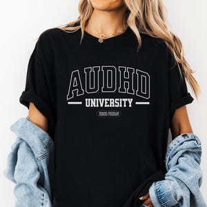 May include: Black t-shirt with white text that reads "AUDHD UNIVERSITY HONORS PROGRAM".