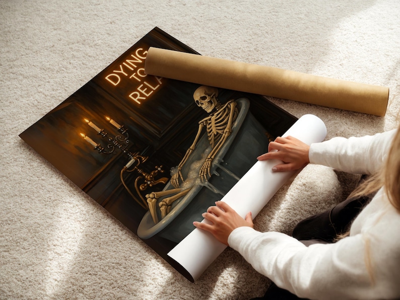 May include: A canvas print featuring a skeleton relaxing in a bathtub, with the words "Dying to Relax" in neon. The artwork includes a candelabra and a vintage bathtub. Two rolled-up posters are next to the print.