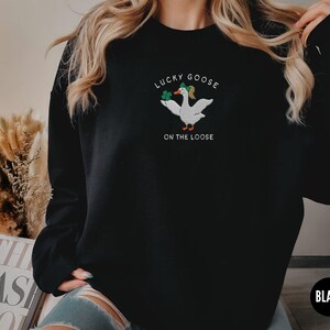 May include: Black sweatshirt with a white goose graphic and the text "Lucky Goose on the Loose".