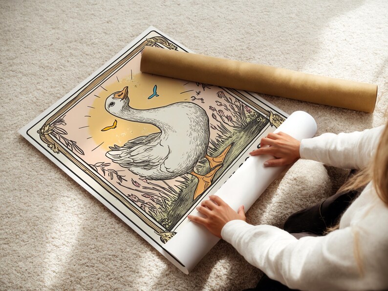 May include: A vintage-style illustration of a white goose with a yellow beak and feet, standing in a field of green grass and flowers. The goose is surrounded by a decorative frame with a light pink background.