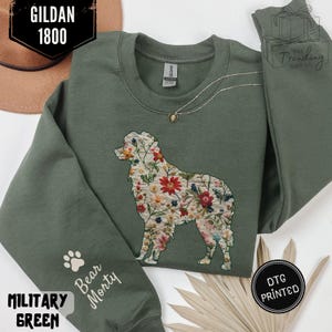 Könnte beinhalten: Militärgrünes Sweatshirt mit floralem Hunde-Design. Das Sweatshirt zeigt den Text "Bear Morty" auf dem Ärmel und "DTG Printed" auf einem schwarzen Kreis. Der Markenname "Gildan 1800" ist ebenfalls sichtbar.