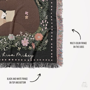 May include: Black and white throw blanket with a floral design and two bears hugging. The blanket has a black and white fringe on the top and bottom and a multi-colour fringe on the sides. The blanket has the text "Lisa. Mikey" on it.