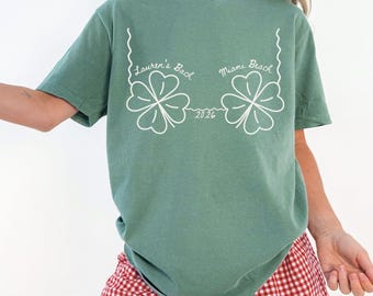 May include: Light green t-shirt with white text and a four-leaf clover design. The text reads "Lauren's Bach Miami Beach 2026". The shirt is paired with red and white checkered shorts. The words "LIGHT GREEN" are at the bottom.