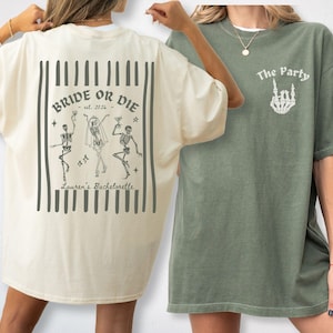May include: An ivory t-shirt featuring a back graphic of three skeletons with the text Bride or Die, est. 2026, and Lauren's Bachelorette, and a moss green t-shirt with a front graphic of a skeleton hand and the text The Party.