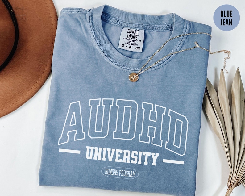 May include: A blue jean t-shirt with white text that reads "AUDHD UNIVERSITY HONORS PROGRAM".