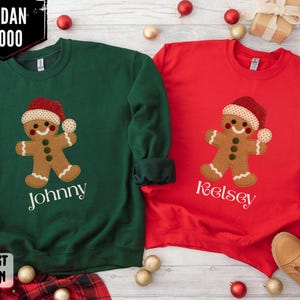 Può includere: Due felpe natalizie, una verde foresta e una rossa, ciascuna con un disegno di omino di pan di zenzero. La felpa verde ha il nome "Johnny" e quella rossa "Kelsey". Entrambi gli omini di pan di zenzero indossano cappelli di Babbo Natale.