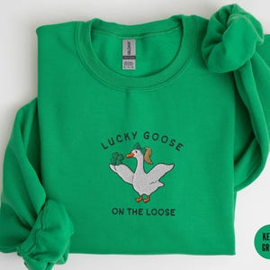 May include: A kelly green sweatshirt with a white embroidered goose wearing a shamrock hat and the text "Lucky Goose on the Loose".
