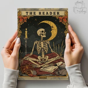 May include: A tarot card print featuring a skeleton in a meditative pose, with a crescent moon and candle in the background. The card is titled "THE READER" and includes the word "BOOKS" at the bottom. The artwork has a vintage, gothic aesthetic.