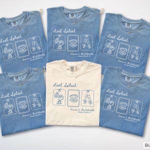 Könnte beinhalten: Eine Auswahl an blau-jeansfarbenen und elfenbeinfarbenen T-Shirts. Jedes Shirt zeigt den Schriftzug "Last Splash" und eine Grafik mit Cocktail, Muschel und Sektgläsern. Der Text "Lauren's Bachelorette Miami Beach, FL" ist ebenfalls vorhanden.