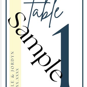 May include: White table number card with navy blue border and text. The word "table" is in a script font, and the number "1" is in a bold sans-serif font. The word "Sample" is written diagonally across the card. A vertical yellow stripe is on the left side with names and a date.