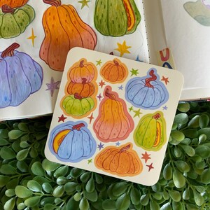 May include: A sheet of stickers featuring various colorful pumpkins in different shapes and sizes. The stickers are on a white background with a few stars.