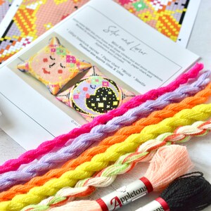 May include: A craft kit labeled "Star and Lunar" with a finished size of approximately 4 inches x 4 inches. The kit includes a paper chart, wools, and a needle. Colorful embroidery floss in shades of pink, purple, orange, yellow, and peach are also visible.