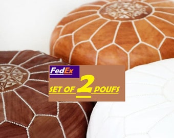 Può includere: Set di due pouf rotondi nei toni del marrone e del bianco. I pouf presentano motivi geometrici e dettagli di cucitura. L'immagine include un logo FedEx e il testo "SET OF 2 POUFS".